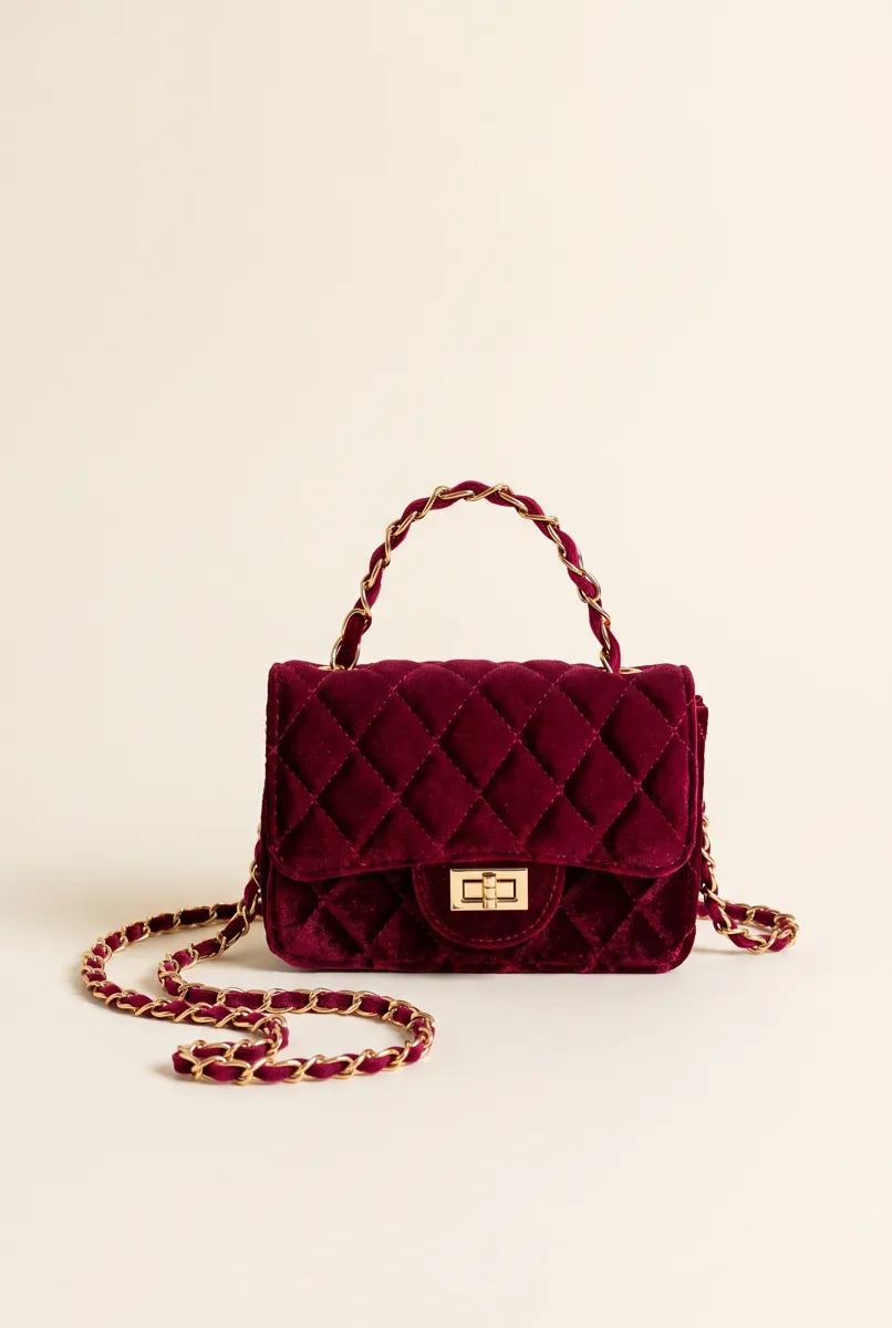 Bezza's own product photo of a quilted burgundy velvet purse with a chain strap